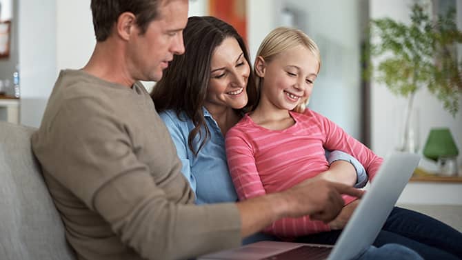 Yksityinen blogi estää tuntemattomia käyttäjiä keräämästä henkilökohtaista tietoa perheestäsi. Kuva kahdesta vanhemmasta istumassa sohvalla yhdessä tyttärensä kanssa tablet-laitetta katsellen.